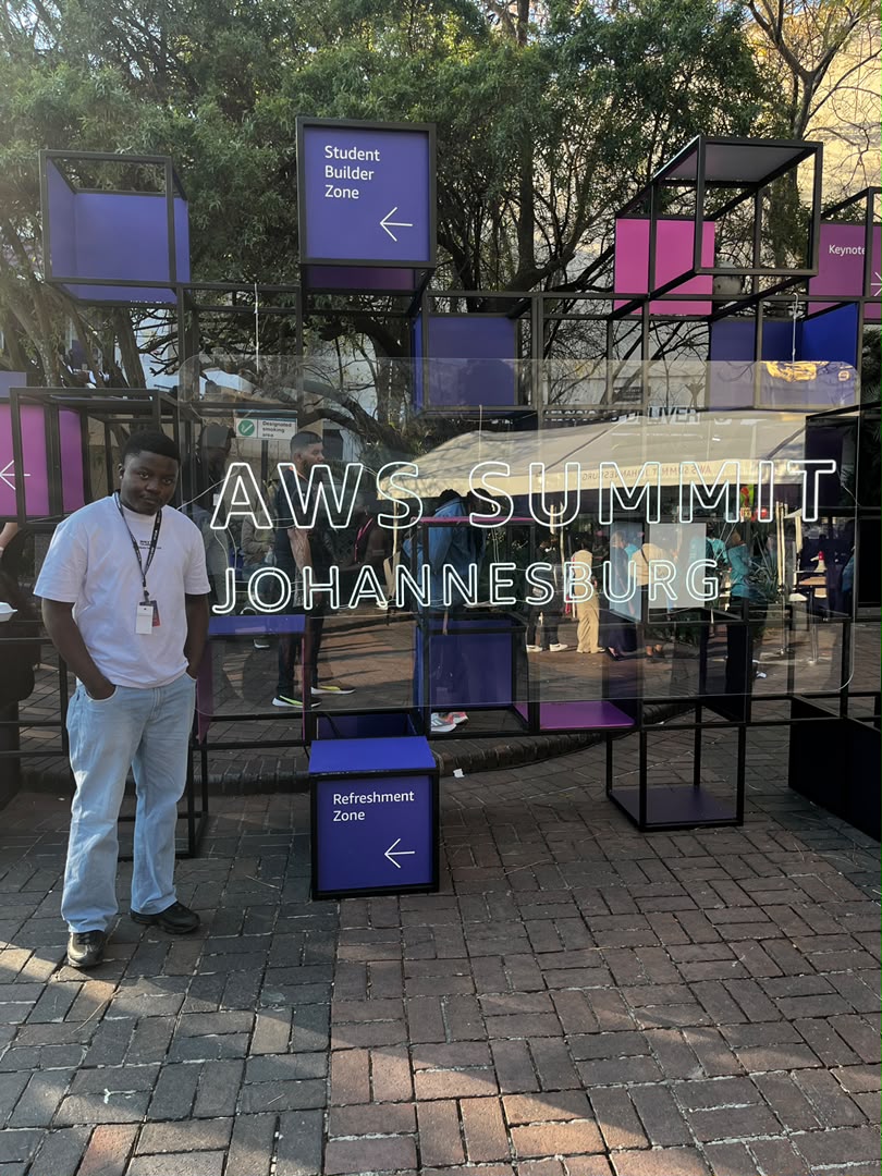 Kupela beside the AWS Summit Johannesburg signage at the venue entrance